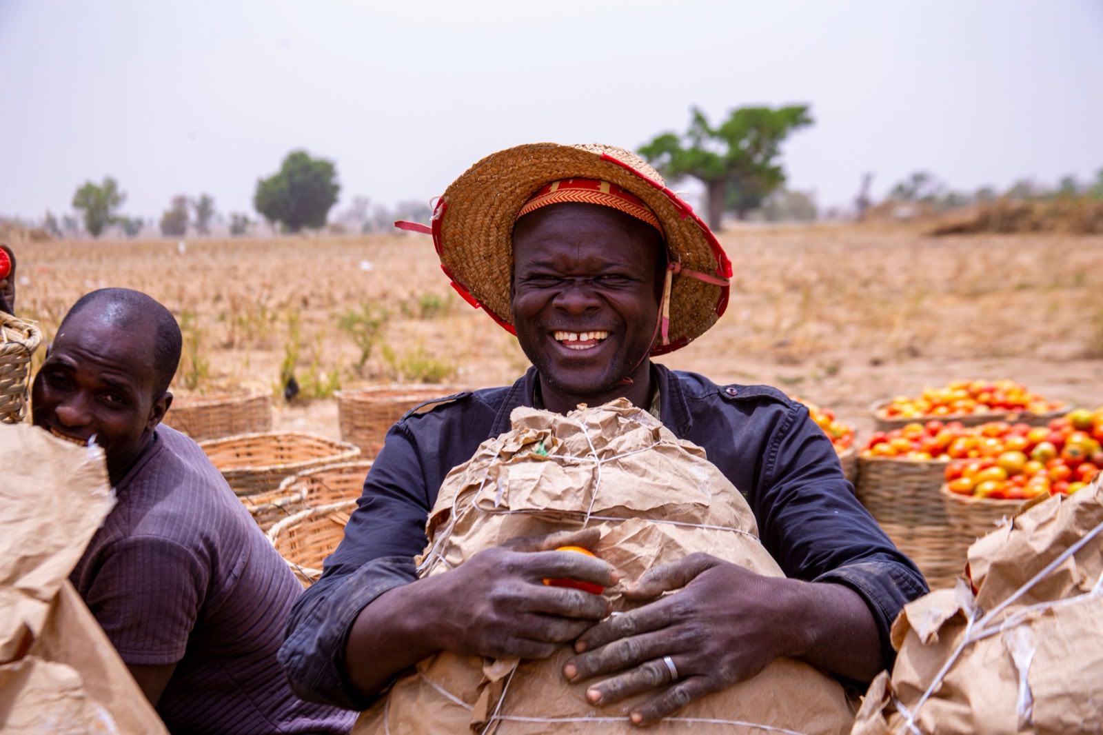 A smiling farmer holding a sack of produce
